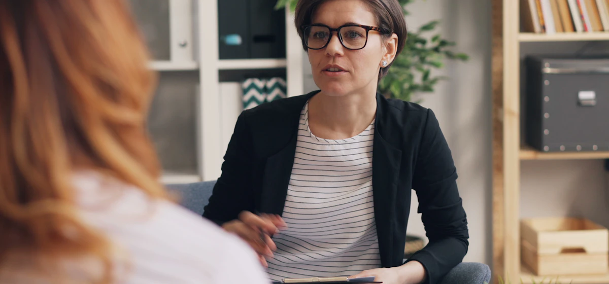 Therapist in glasses talking with a client during a session