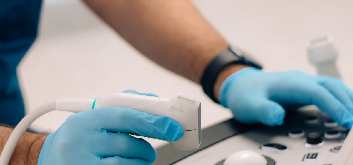 Gloved hands operating an ultrasound probe and console
