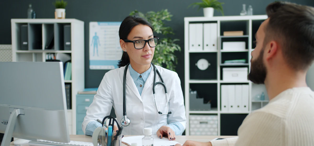 Doctor talking with an adult patient across her desk