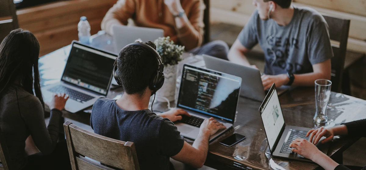 Developers working on laptops around a shared table