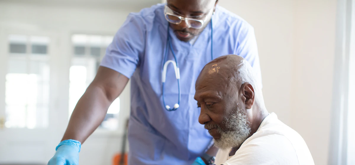 Nurse in scrubs attending to an older male patient